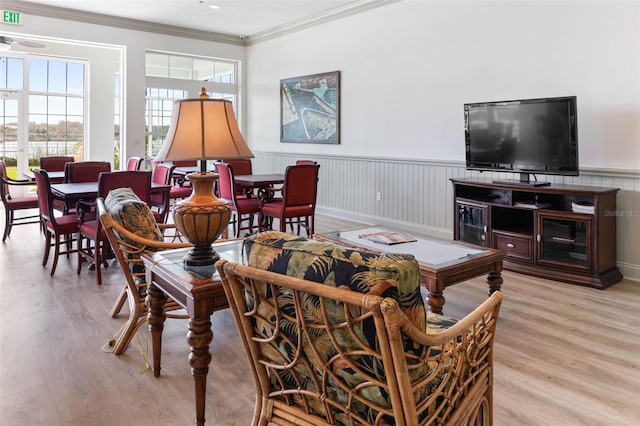 living area featuring ornamental molding, a wainscoted wall, and wood finished floors