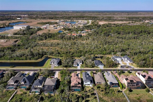 drone / aerial view featuring a water view, a wooded view, and a residential view