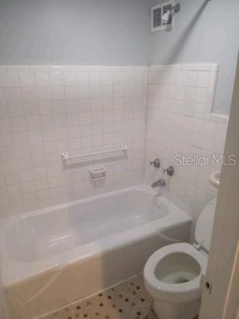 bathroom featuring tub / shower combination and toilet