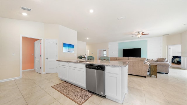 kitchen featuring stainless steel dishwasher, white cabinets, sink, light stone counters, and a center island with sink