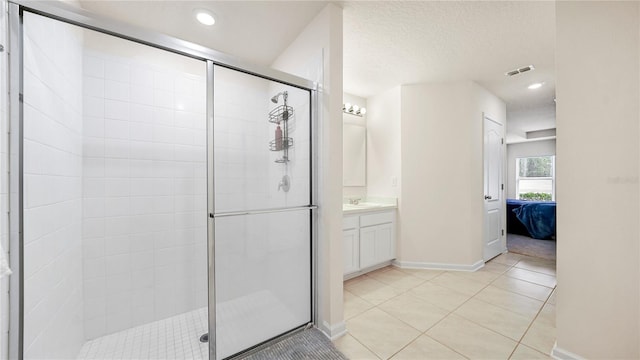 bathroom featuring a shower with door, a textured ceiling, tile patterned flooring, and vanity