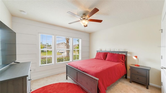 carpeted bedroom featuring ceiling fan and a textured ceiling