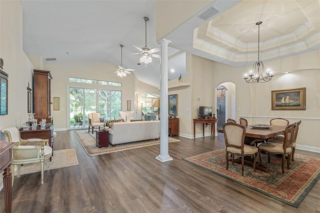 dining space with decorative columns, ceiling fan with notable chandelier, a high ceiling, and dark hardwood / wood-style flooring