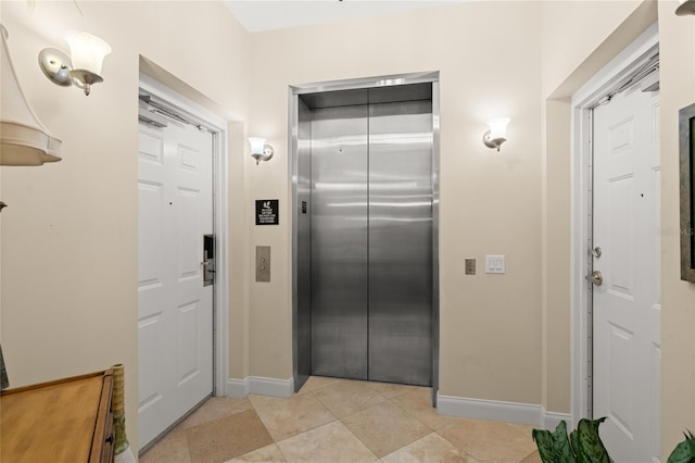 kitchen with elevator, light tile patterned floors, and baseboards