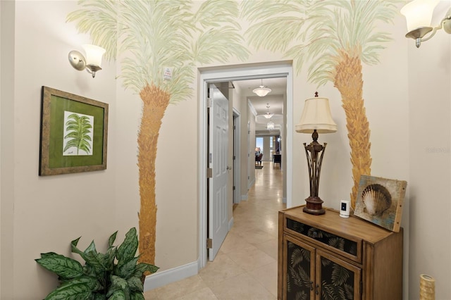 hallway with baseboards, light tile patterned floors, and wallpapered walls