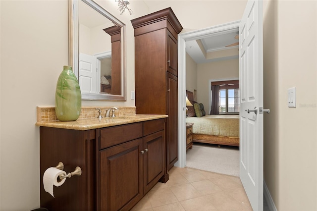 ensuite bathroom featuring ensuite bathroom, vanity, ornamental molding, backsplash, and a raised ceiling