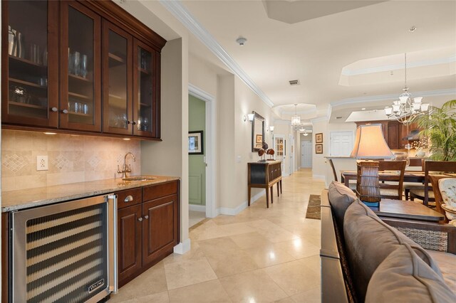 bar featuring wine cooler, tasteful backsplash, ornamental molding, a sink, and a chandelier