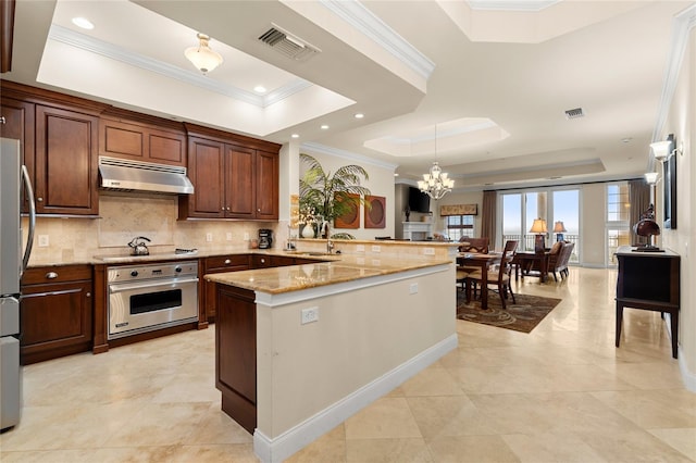 kitchen featuring under cabinet range hood, visible vents, appliances with stainless steel finishes, and a raised ceiling