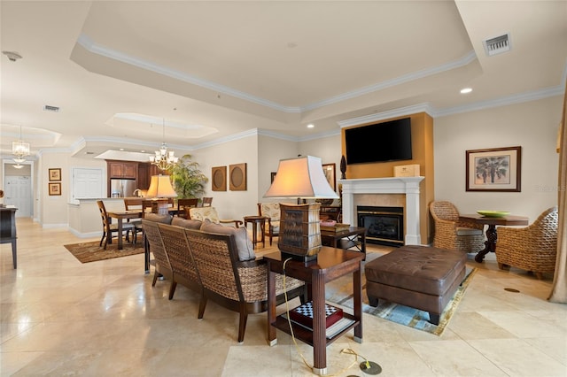 living room featuring a chandelier, a glass covered fireplace, a raised ceiling, and visible vents