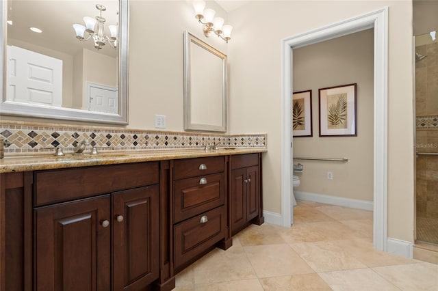 full bath with double vanity, tasteful backsplash, tiled shower, toilet, and a notable chandelier