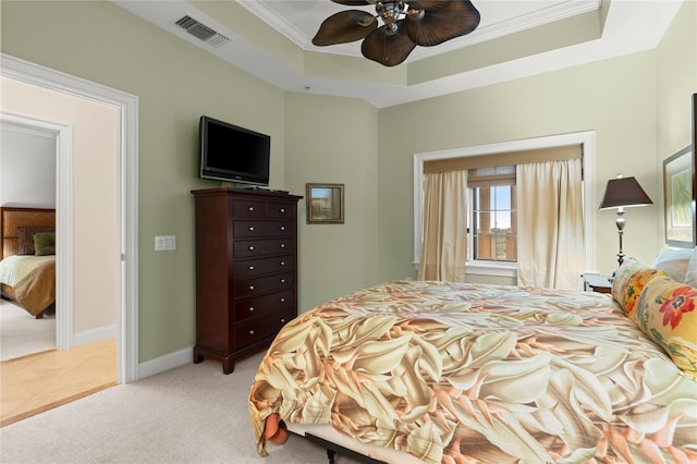 bedroom with a raised ceiling, light colored carpet, visible vents, ornamental molding, and baseboards