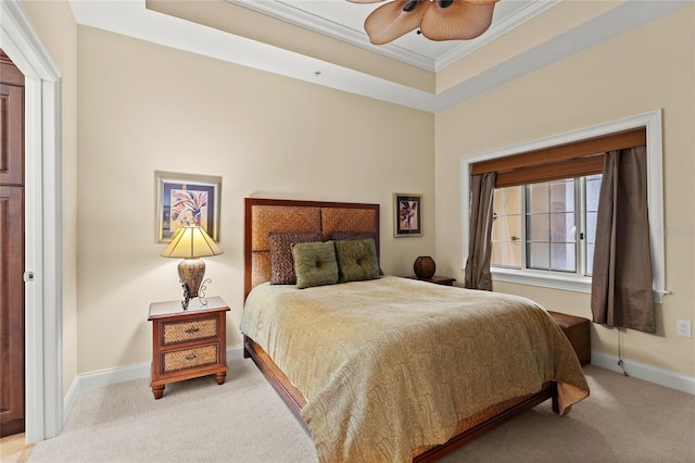 bedroom featuring a raised ceiling, light colored carpet, ornamental molding, a ceiling fan, and baseboards