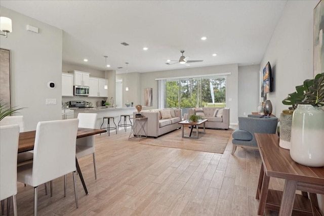 living room with light hardwood / wood-style floors and ceiling fan