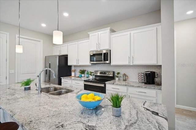 kitchen featuring decorative light fixtures, a center island with sink, white cabinetry, and stainless steel appliances