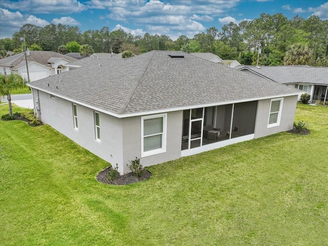 rear view of house featuring a sunroom and a lawn