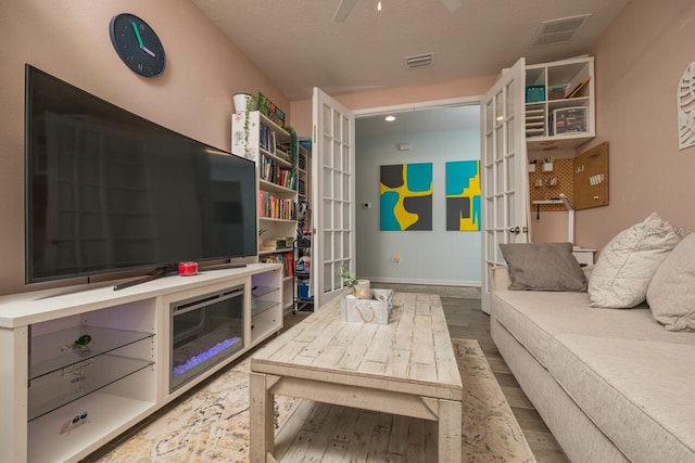 living room featuring ceiling fan, hardwood / wood-style floors, and a textured ceiling