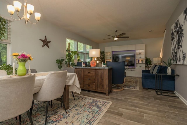 dining area with ceiling fan with notable chandelier and hardwood / wood-style floors