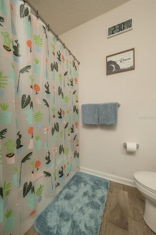 bathroom featuring hardwood / wood-style floors, toilet, a textured ceiling, and a shower with shower curtain