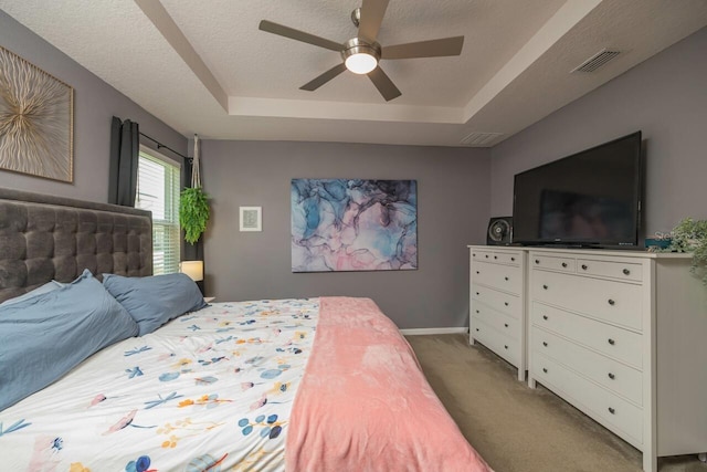 carpeted bedroom with ceiling fan, a raised ceiling, and a textured ceiling