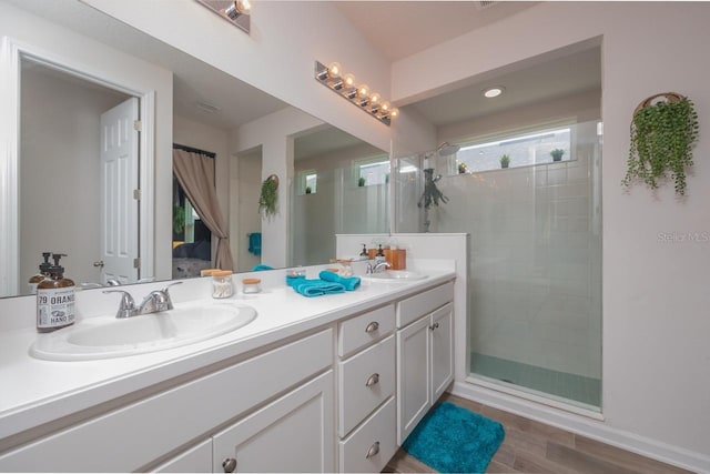 bathroom with hardwood / wood-style floors, a shower with door, and vanity