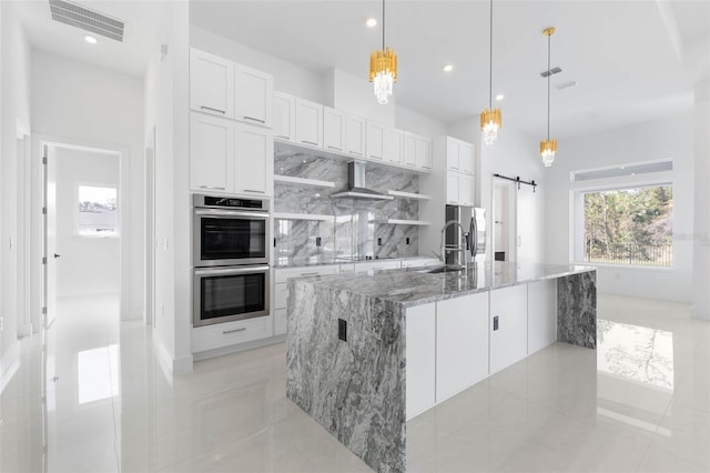 kitchen featuring pendant lighting, stainless steel appliances, a barn door, and white cabinets