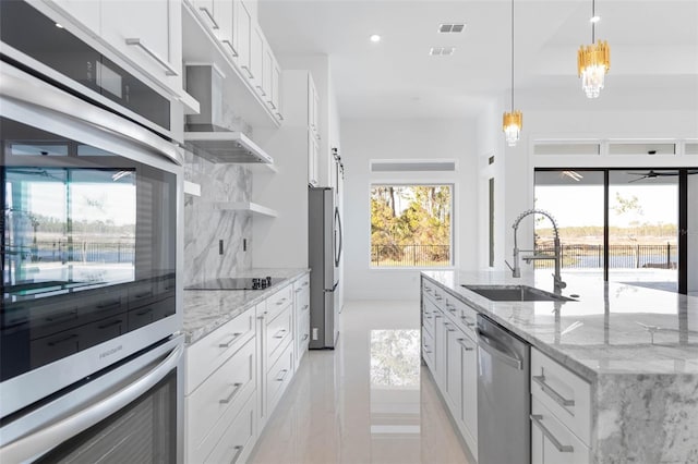 kitchen featuring appliances with stainless steel finishes, decorative light fixtures, sink, white cabinets, and light stone counters