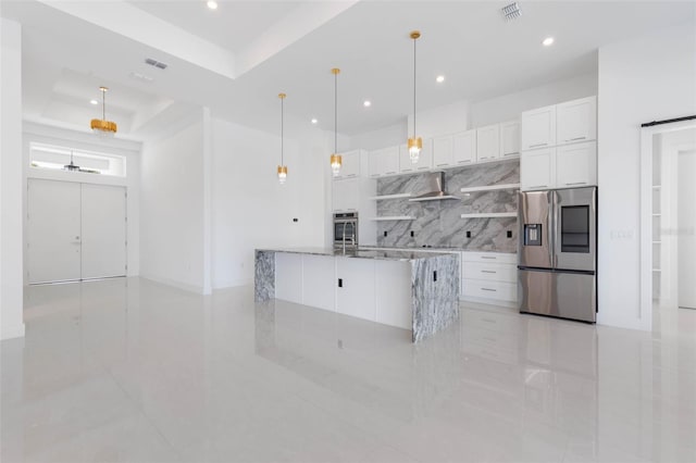 kitchen featuring pendant lighting, stainless steel appliances, a tray ceiling, white cabinets, and wall chimney exhaust hood