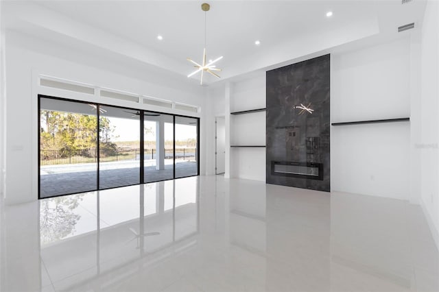 unfurnished room with a tiled fireplace, light tile patterned floors, and an inviting chandelier