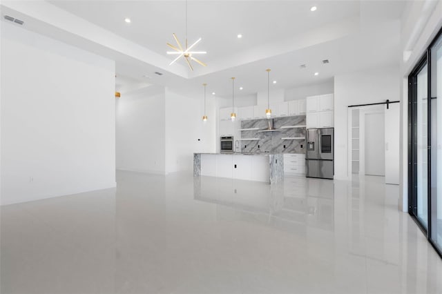 kitchen with appliances with stainless steel finishes, pendant lighting, white cabinets, decorative backsplash, and a barn door