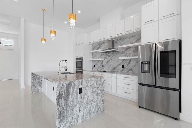 kitchen with appliances with stainless steel finishes, white cabinetry, an island with sink, decorative backsplash, and hanging light fixtures