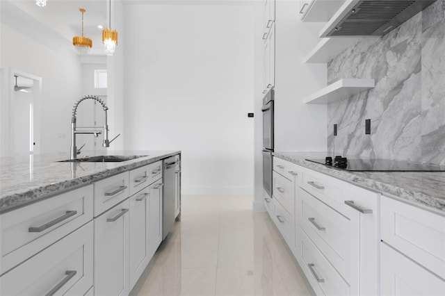 kitchen featuring hanging light fixtures, white cabinetry, sink, and wall chimney range hood