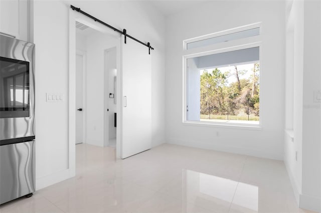 tiled empty room featuring a barn door