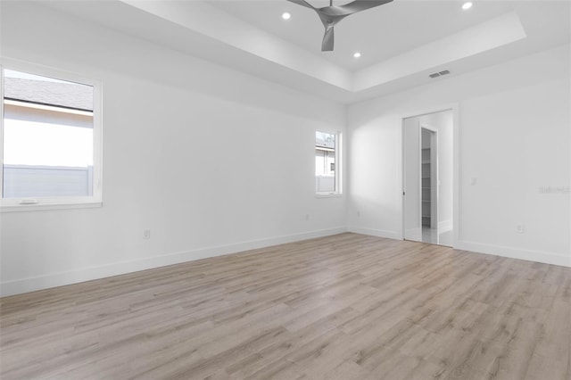 spare room featuring a tray ceiling, light hardwood / wood-style flooring, and ceiling fan