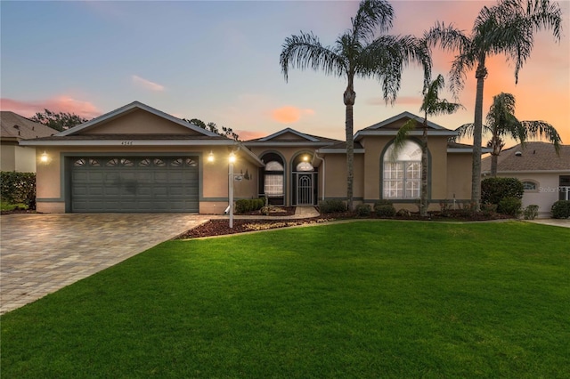 single story home featuring a lawn and a garage