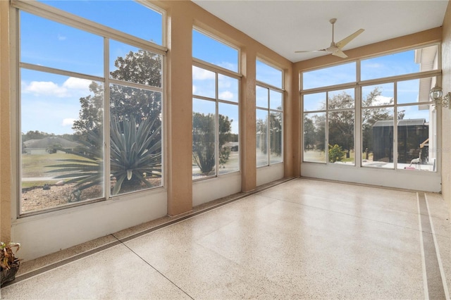 unfurnished sunroom featuring ceiling fan and a healthy amount of sunlight