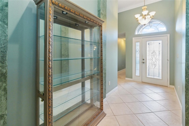 entryway with plenty of natural light, a chandelier, light tile patterned floors, and ornamental molding