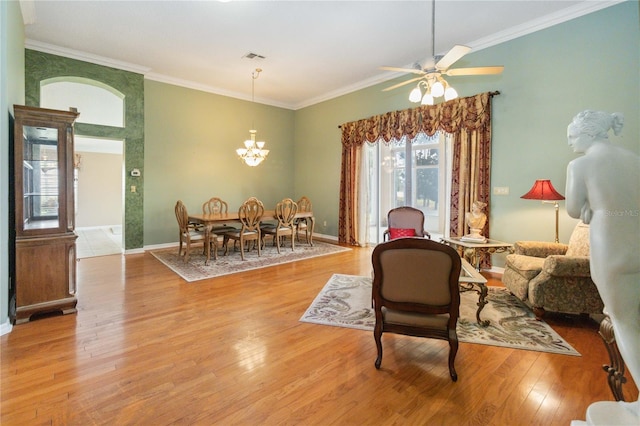 living area featuring ceiling fan with notable chandelier, crown molding, and light wood-type flooring