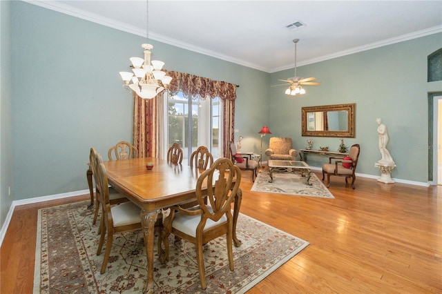 dining space featuring ceiling fan with notable chandelier, light hardwood / wood-style flooring, and crown molding