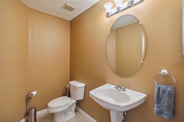 bathroom featuring sink, toilet, a textured ceiling, and tile patterned flooring