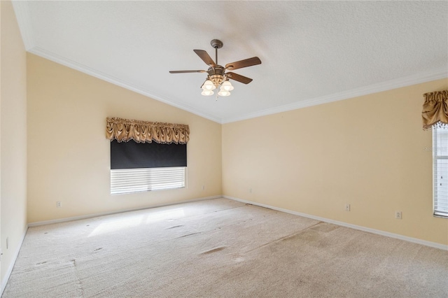 carpeted empty room with crown molding, vaulted ceiling, and ceiling fan