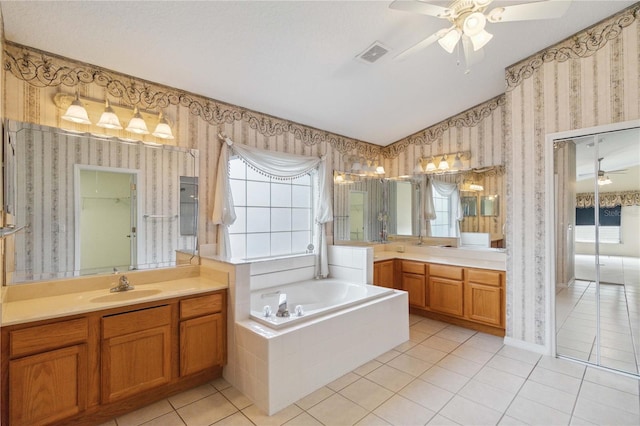 bathroom featuring a wealth of natural light, tile patterned floors, vanity, and tiled tub