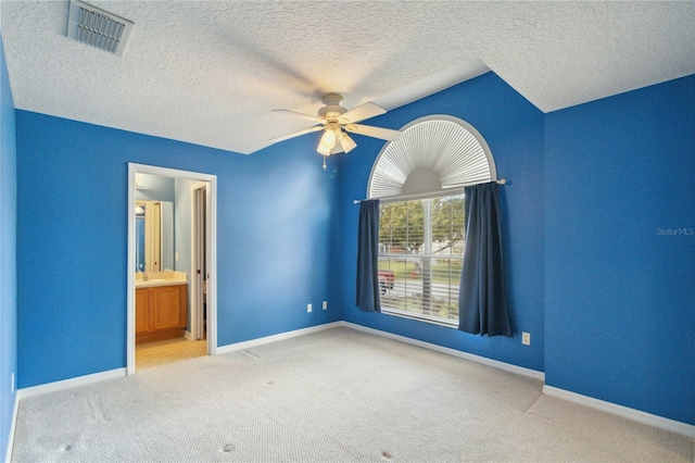 unfurnished bedroom with ensuite bathroom, a textured ceiling, light carpet, sink, and ceiling fan