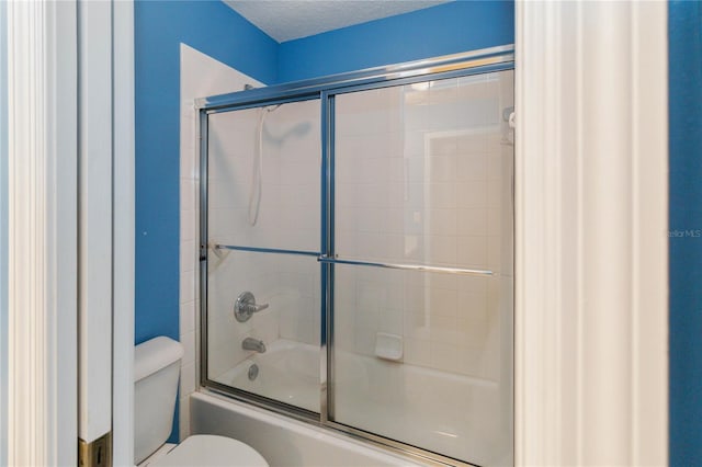 bathroom featuring a textured ceiling, enclosed tub / shower combo, and toilet