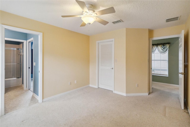 unfurnished bedroom with ceiling fan, a textured ceiling, and light carpet