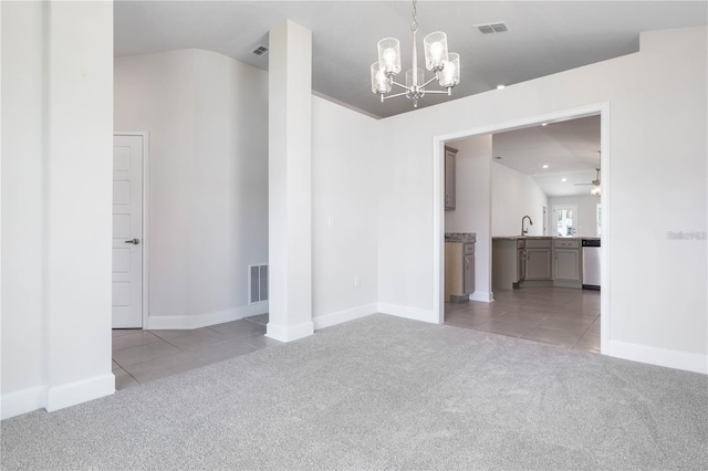 spare room featuring light carpet, sink, and ceiling fan with notable chandelier