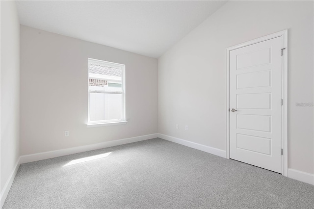 carpeted spare room featuring vaulted ceiling