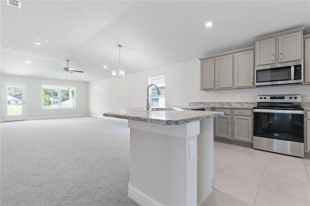 kitchen with hanging light fixtures, sink, light colored carpet, gray cabinetry, and stainless steel appliances