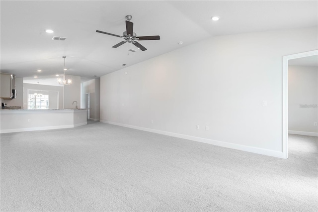 unfurnished living room with light carpet, ceiling fan with notable chandelier, and lofted ceiling