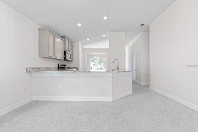 kitchen with kitchen peninsula, sink, light colored carpet, and stainless steel appliances