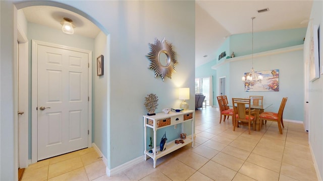 tiled foyer with vaulted ceiling and a chandelier